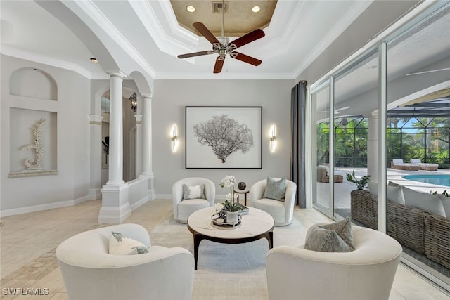 living room featuring a raised ceiling, ornate columns, crown molding, light tile patterned floors, and ceiling fan