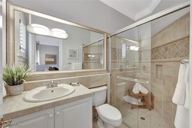 bathroom featuring ornamental molding, vanity, a shower with shower door, and toilet