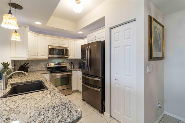 kitchen featuring tasteful backsplash, stainless steel appliances, sink, decorative light fixtures, and light tile patterned flooring