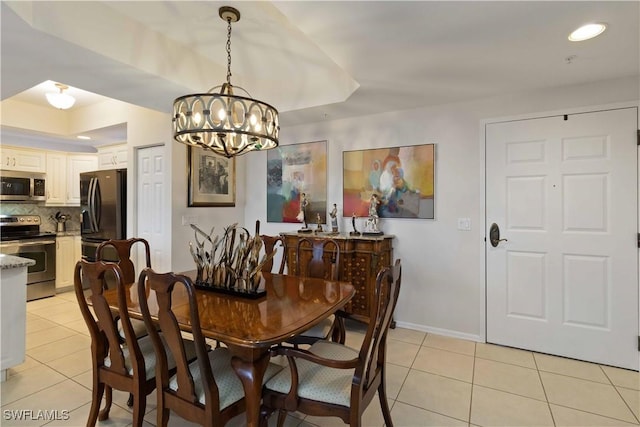 tiled dining area featuring a raised ceiling and a notable chandelier