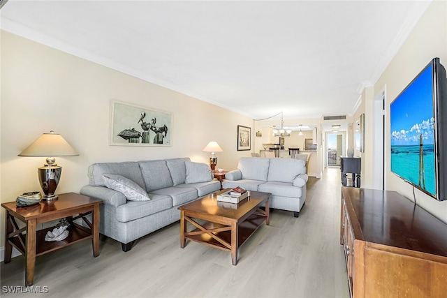 living room featuring crown molding, light hardwood / wood-style flooring, and a notable chandelier