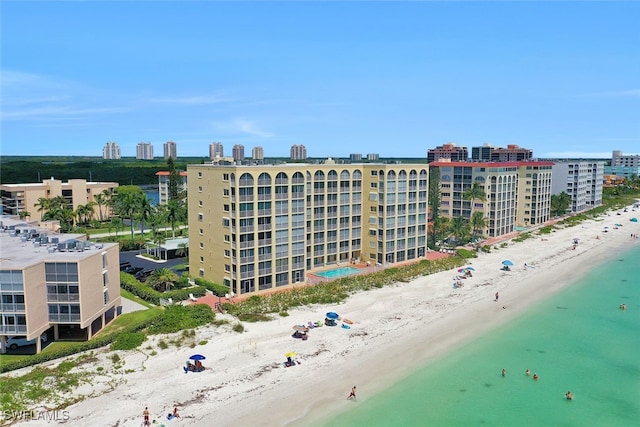 view of building exterior featuring a water view and a beach view