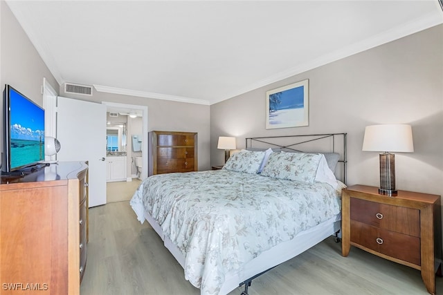 bedroom featuring connected bathroom, light hardwood / wood-style flooring, and crown molding