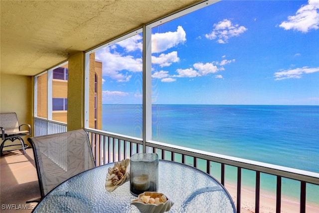 sunroom featuring a water view and a beach view