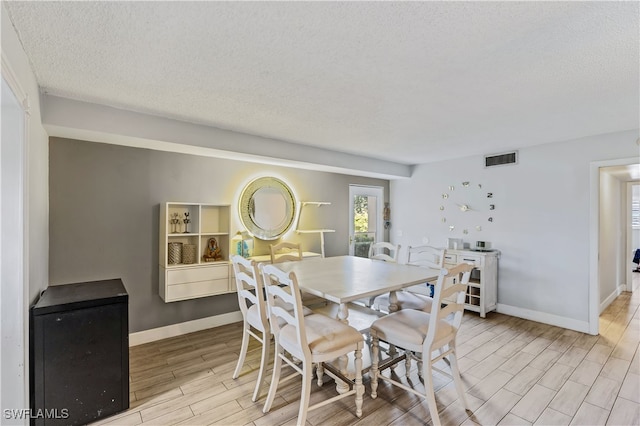 dining area with a textured ceiling and light hardwood / wood-style floors