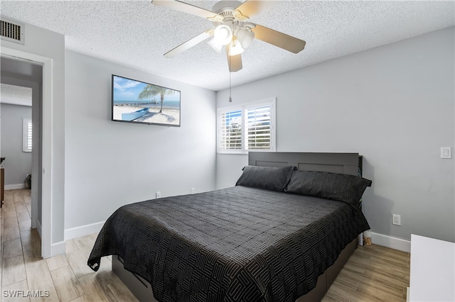 bedroom with ceiling fan, a textured ceiling, and light hardwood / wood-style flooring