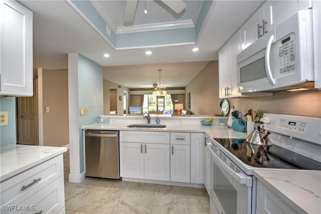 kitchen with white appliances, ornamental molding, a tray ceiling, white cabinets, and sink