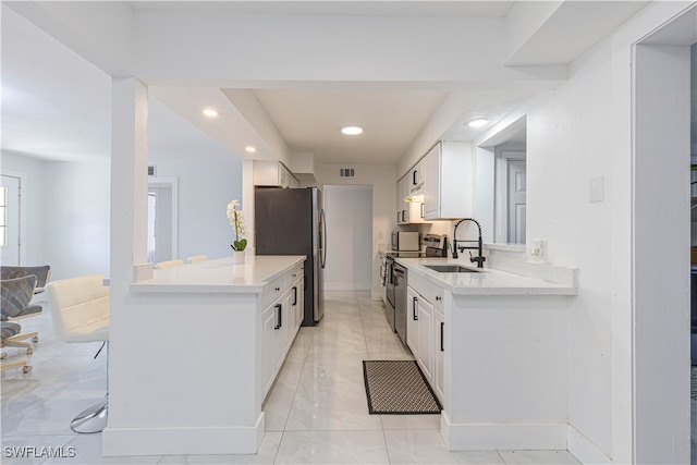 kitchen with sink, appliances with stainless steel finishes, kitchen peninsula, and white cabinets