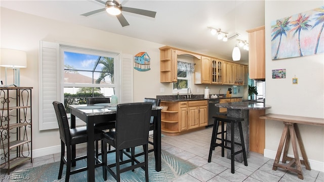 kitchen featuring dishwasher, ceiling fan, sink, and a breakfast bar