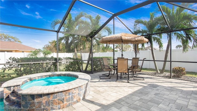 view of pool featuring a patio, glass enclosure, and an in ground hot tub