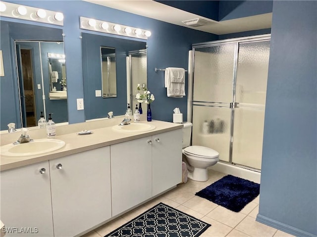 bathroom with a shower stall, tile patterned flooring, double vanity, and toilet