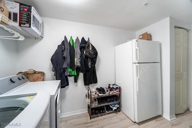 laundry area featuring washer and dryer, a textured ceiling, and light wood-type flooring