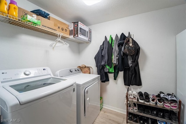 clothes washing area with light hardwood / wood-style floors and separate washer and dryer