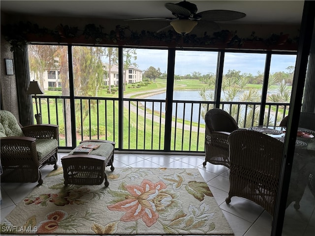 sunroom with ceiling fan and a water view