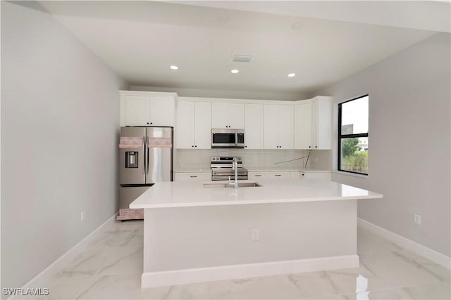 kitchen with stainless steel appliances, a center island with sink, and white cabinetry