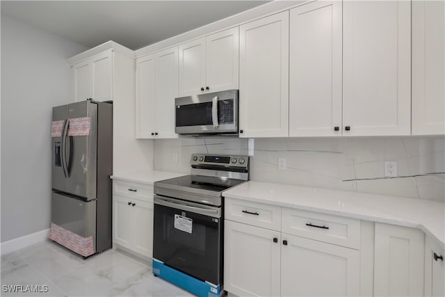 kitchen with white cabinetry, backsplash, light stone counters, and appliances with stainless steel finishes