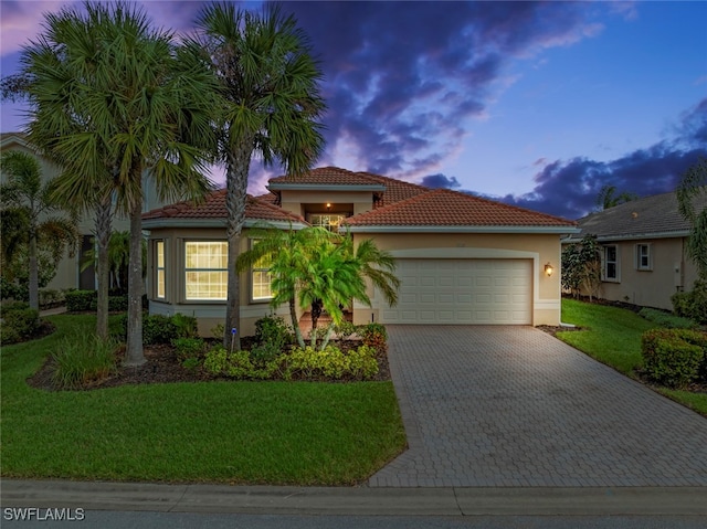 mediterranean / spanish-style home with a yard and a garage