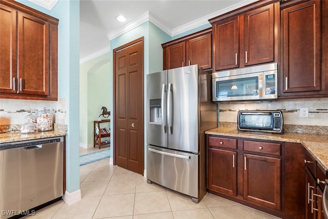 kitchen featuring crown molding, light tile patterned floors, light stone counters, decorative backsplash, and stainless steel appliances