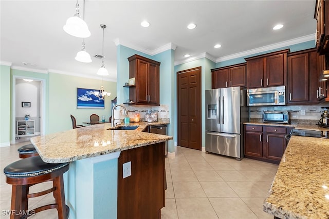 kitchen featuring appliances with stainless steel finishes, hanging light fixtures, decorative backsplash, sink, and a breakfast bar