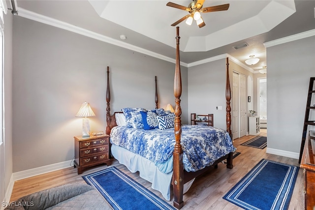 bedroom featuring ensuite bath, a closet, ornamental molding, ceiling fan, and a tray ceiling