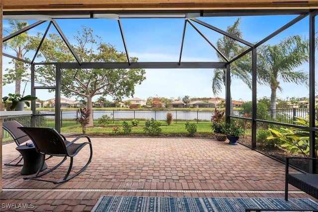 view of patio / terrace featuring glass enclosure and a water view