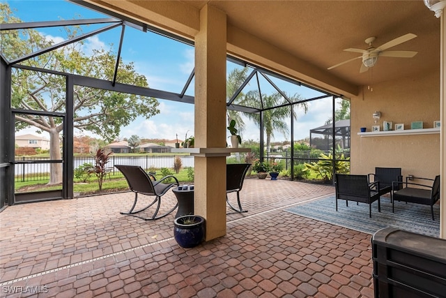 view of patio featuring glass enclosure, ceiling fan, and a water view