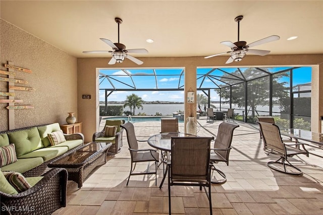 sunroom / solarium with plenty of natural light, a water view, and a ceiling fan