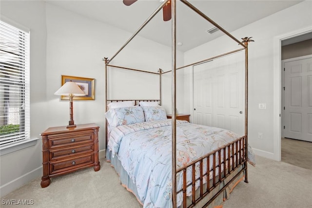 bedroom featuring light carpet, ceiling fan, baseboards, and a closet