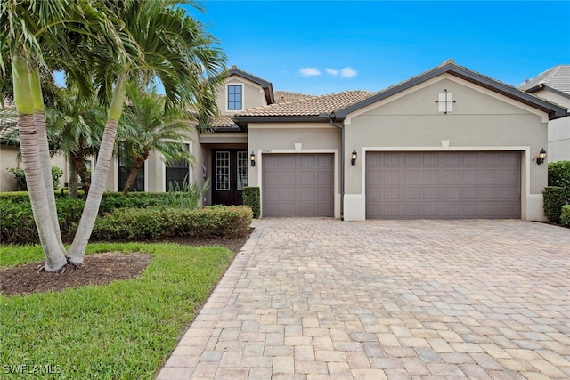 view of front of property with an attached garage, a tiled roof, decorative driveway, and stucco siding