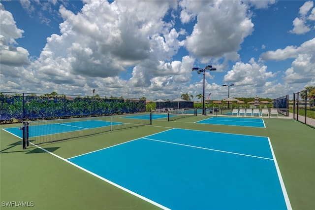 view of tennis court with community basketball court and fence