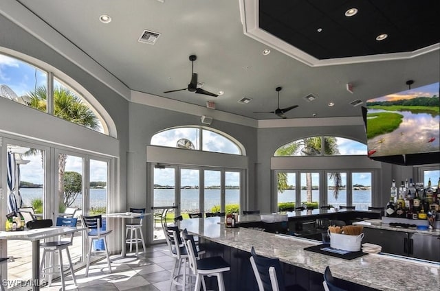 exterior space featuring light stone counters, french doors, a water view, visible vents, and ceiling fan