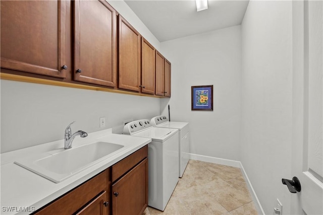 washroom featuring cabinet space, baseboards, washer and dryer, and a sink