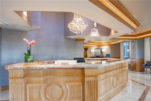 kitchen featuring light brown cabinetry, a chandelier, a center island, a raised ceiling, and light stone countertops