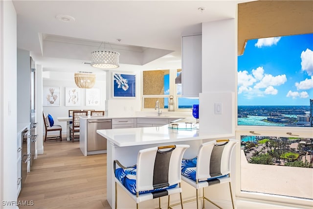 kitchen with pendant lighting, white cabinetry, a breakfast bar area, stainless steel dishwasher, and kitchen peninsula