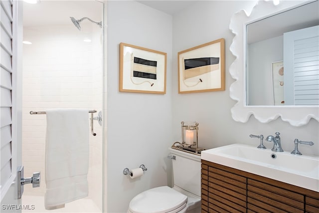 bathroom with vanity, tiled shower, and toilet