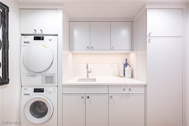 laundry room featuring sink, cabinets, and stacked washing maching and dryer