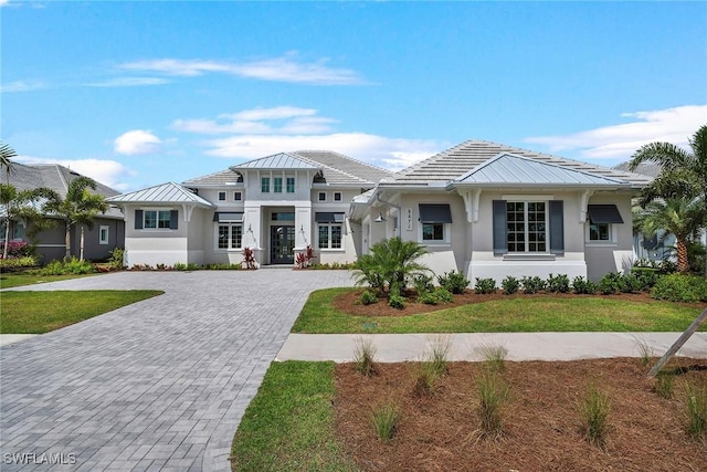 8871 Nevis Way, Naples, FL 34112 - view of front of home featuring a standing seam roof, stucco siding, decorative driveway, and a front yard