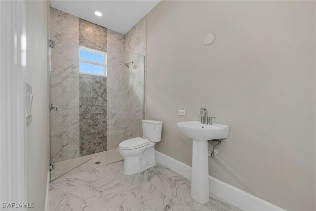 bathroom with a tile shower and toilet