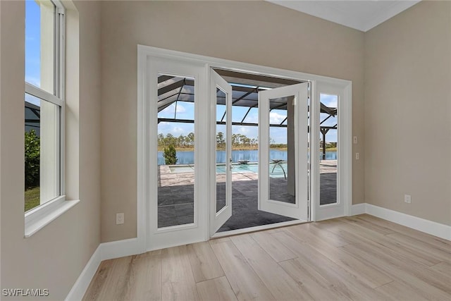 8871 Nevis Way, Naples, FL 34112 - doorway to outside featuring a water view, a healthy amount of sunlight, and wood finished floors