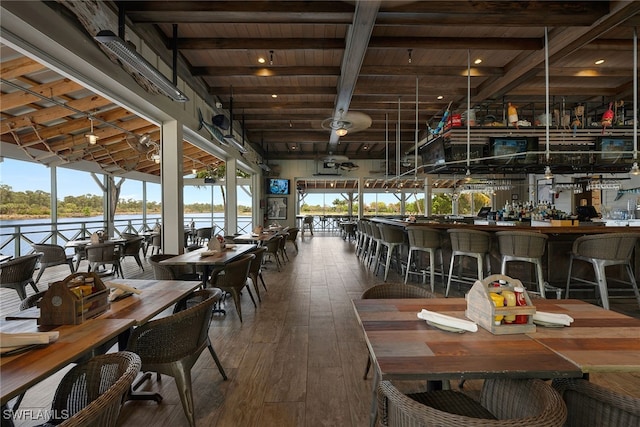 dining area featuring a water view, beam ceiling, wood-type flooring, and wood ceiling