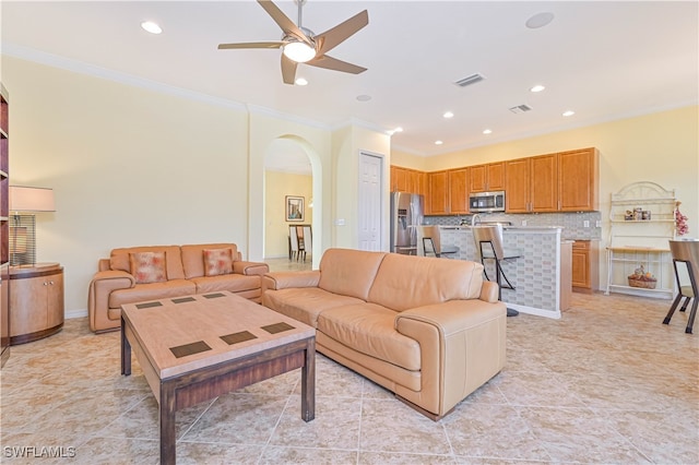 tiled living room with ornamental molding and ceiling fan