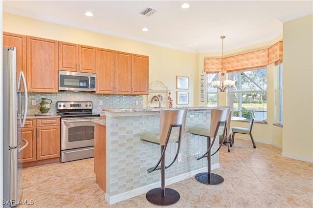 kitchen with a notable chandelier, light stone counters, appliances with stainless steel finishes, crown molding, and decorative light fixtures