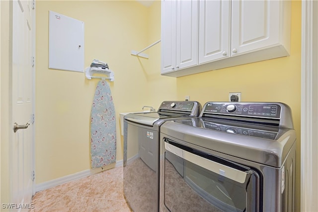 laundry area with cabinets, washer and dryer, and light tile patterned floors