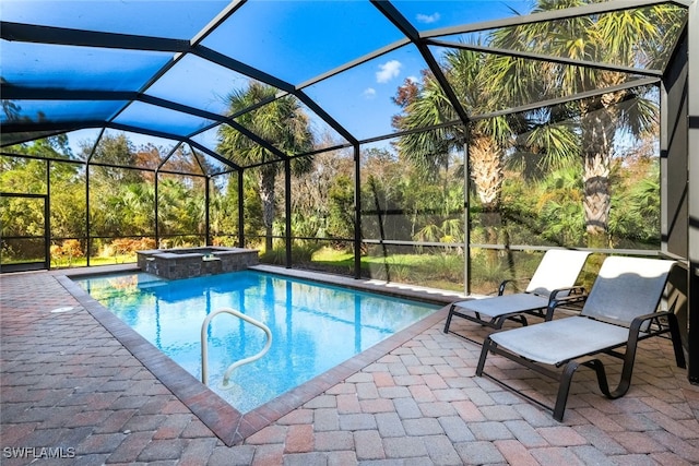 view of pool with an in ground hot tub, a patio area, and glass enclosure