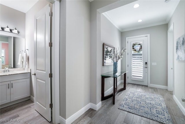 entrance foyer with light hardwood / wood-style floors, crown molding, and sink