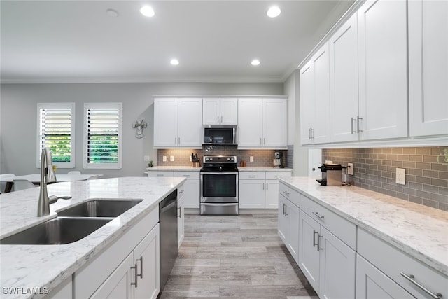 kitchen with white cabinetry, ornamental molding, stainless steel appliances, and sink