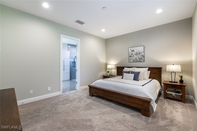 bedroom with ensuite bath and light colored carpet