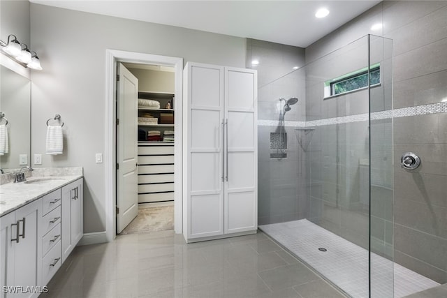 bathroom with vanity, tiled shower, and tile patterned flooring