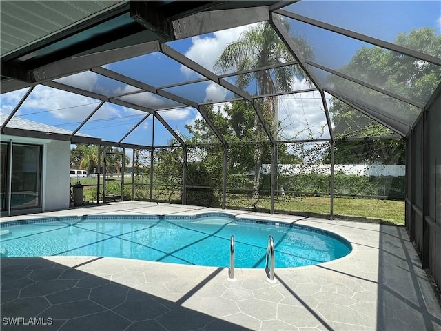 view of pool with glass enclosure and a patio area