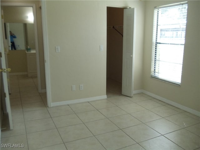 unfurnished bedroom with a spacious closet, light tile patterned flooring, and a closet